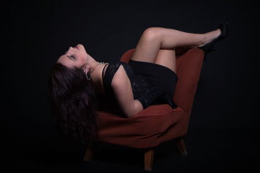 Young woman in retro clothes sitting on old orange chair