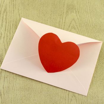 red heart with pink envelope on wooden background