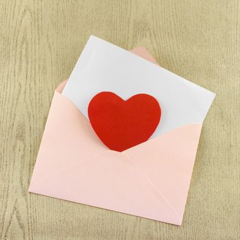 red heart with pink envelope on wooden background