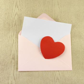 red heart with pink envelope on wooden background