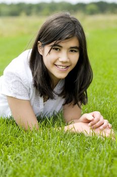 Beautiful biracial teen girl relaxing on lush green grass