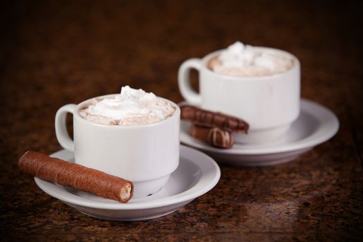 Two cups of coffee or hot cocoa with chocolates and  cookies on brown background 