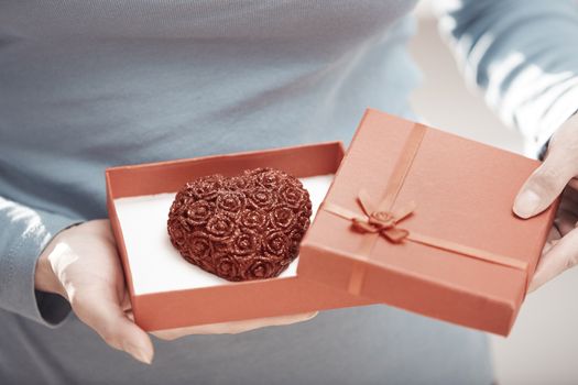 Hands of woman opening gift box with heart