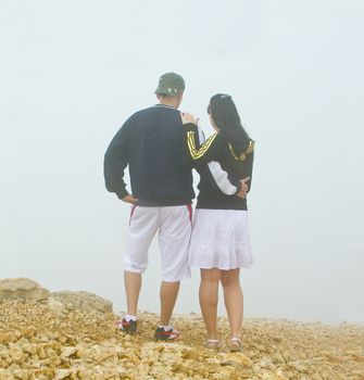 Young couple on mountain looking down on foggy day