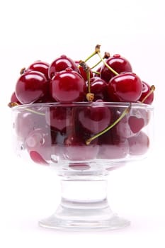 Ripe fresh cherry in the chrystal glass isolated on white background
