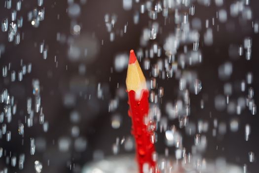 Red crayon under the rain. Close-up view