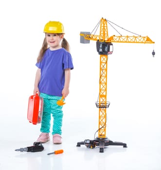 Little builder. Girl in a helmet plays in the builder with tools. Isolated over white.