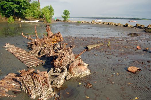 Abandoned rusty metal boat parts at low tide ocean coast, Papua New Guinea