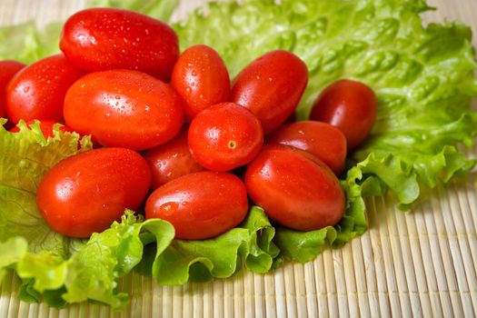 Vegetarian tomato and lettuce on bamboo tray are photographed close-up