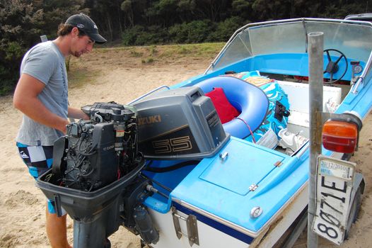 Man works with motor boat, New Zealand
