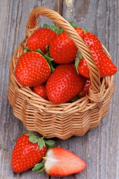 Ripe Strawberries Full of Wicker Basket closeup on Rustic Wooden background