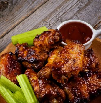 Arrangement of Celery Sticks, Ketchup and Barbecue  Chicken Legs and Wings Barbecue closeup on Wooden Plate