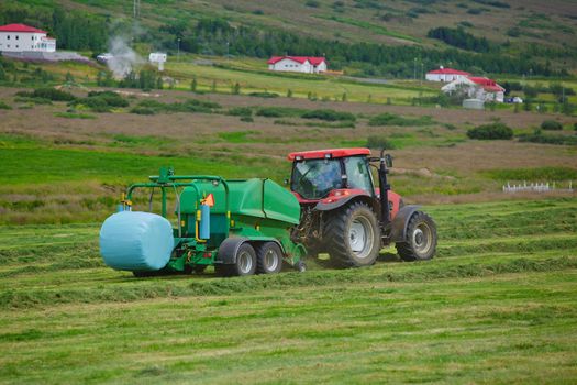 Huge tractor collecting haystack in the field. Iceland.