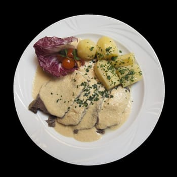 Beef tongue with vegetables isolated over black background