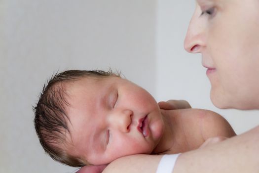 Cute infant sleeping on the mother’s shoulder