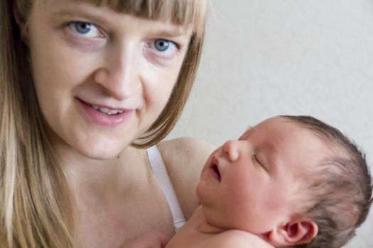 Cute infant sleeping on the mother’s shoulder