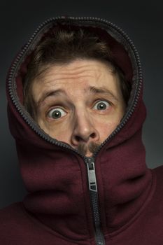 Man in hoody with a look of fear and surprise on his face.