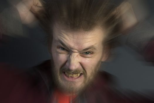 An angry man with a bad temper tearing his hair out.