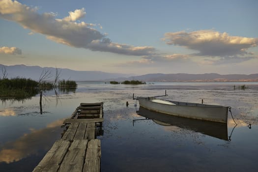 Sunset light behind the lake with boat and dock