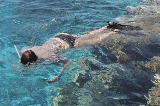 Woman photographer diving into water of Red sea