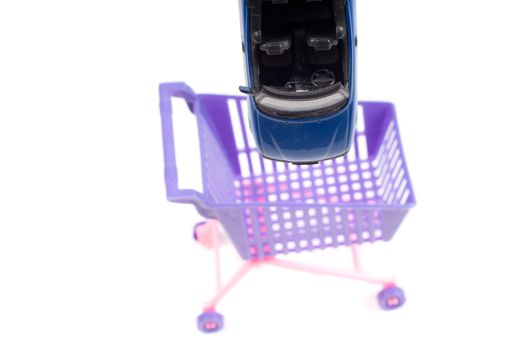 Blue car falling into shopping-cart, isolated on white