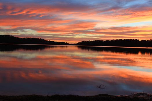 Sunrise and the sky became on fire and mirror reflections in the beautiful Narrabeen Lakes.  Sydney, Australia