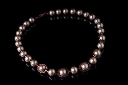Artisian beaded pearl necklace isolated on black background with reflection