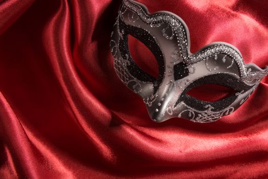 Mardi Gras mask on red satin fabric background