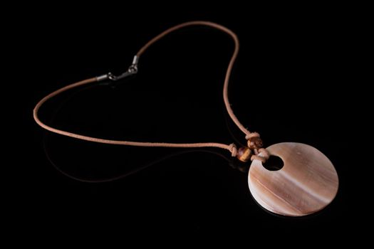 Simple shell necklace isolated on black background with light reflection