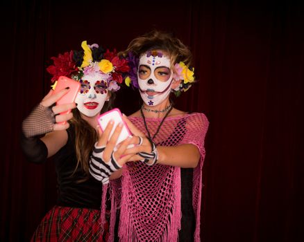 Teens pose in Day fo the Dead costumes and make up for selfies