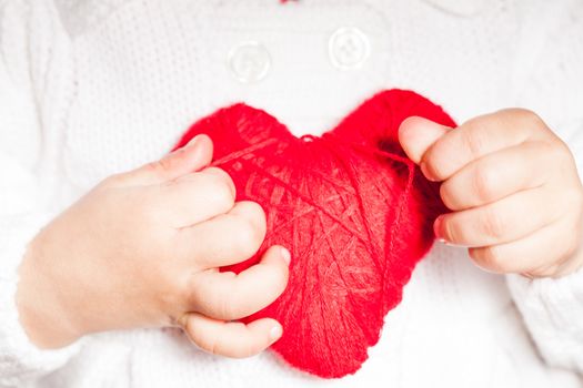 Red heart in hands of little kid in white blouse