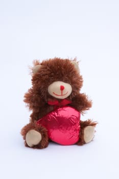 A Valentine's Day Teddy Bear with a red covered chocolate heart.
