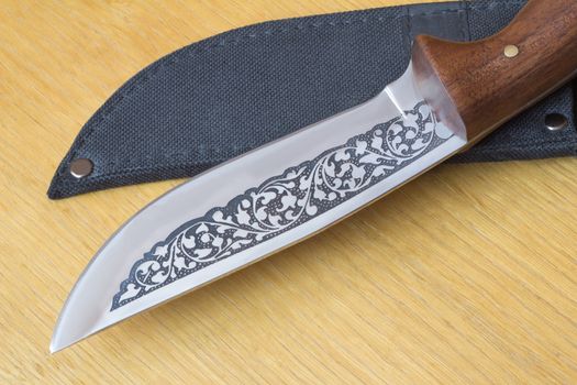 Large, beautifully decorated with a hunting knife and black case for a knife. Located on a cutting Board.