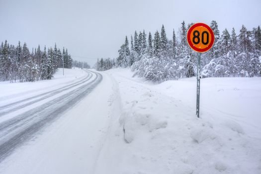 Warning traffic sign on snowy arctic winter road.