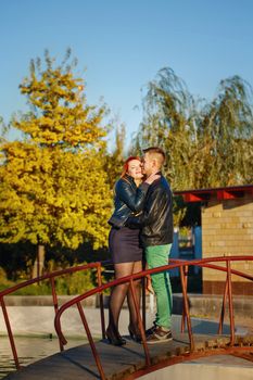 Young couple embracing standing on the bridge in the city park