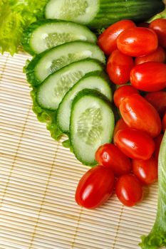 Ripe cherry tomatoes, cucumbers and lettuce closeup shot