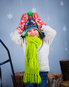 Winter Fashion. Portrait of adorable happy boy in winter hat gloves and sweater in studio.