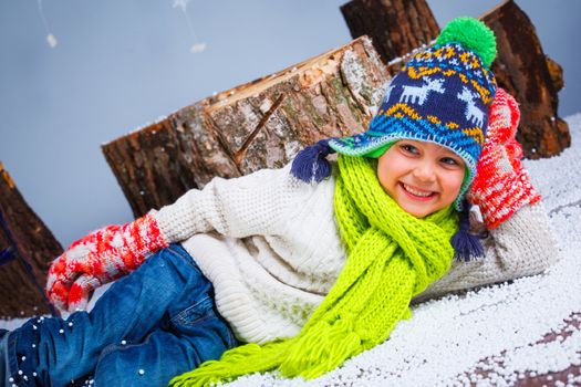 Winter Fashion. Adorable happy boy in winter hat gloves and sweater in studio.