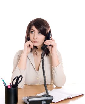 Portrait of a pretty business woman at office desk writing on document while talking on telephone