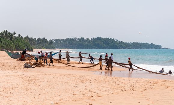 KOSGODA, SRI LANKA - FEBRUARY 23: Local fishermen pull a fishing net from Indian Ocean on February 23, 2013 in Kosgoda, Sri Lanka. Fishing in Sri Lanka is the way they earn their living.