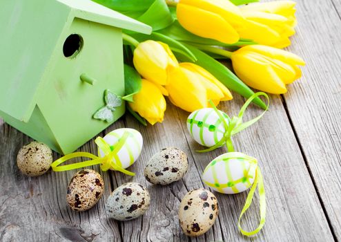 quail eggs with tulips and birdhouse, on wooden background