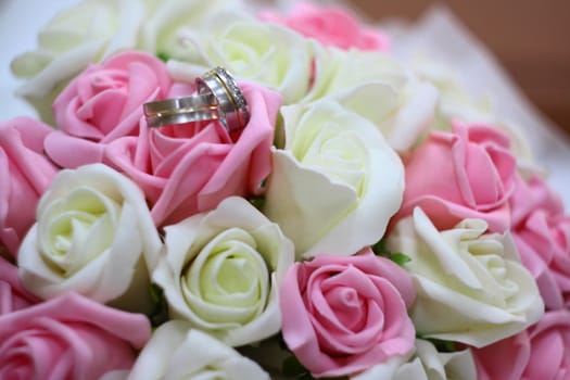 rings on beautiful wedding bouquet with white and pink roses