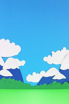 Paper landscape with mountains, trees, clouds and meadow