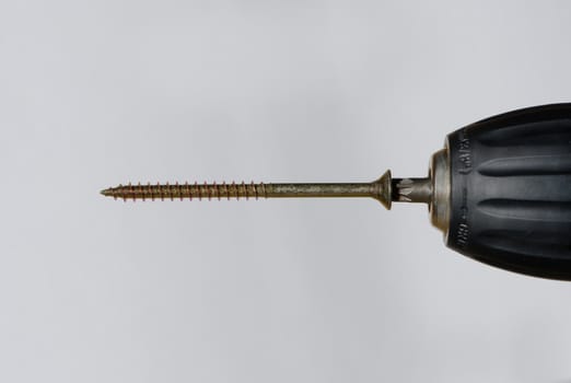 Electric drill with a long screw on a white background