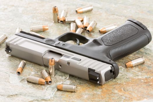 Handgun surrounded with scattered bullets littering the top of an old grungy wooden surface depicting crime, terrorism and violence or protection of personal assets