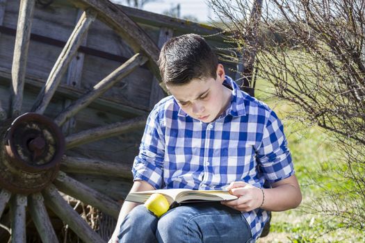 Student.Young man reading a book in outdoor with yellow apple.