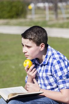 Looking.Young man reading a book in outdoor with yellow apple.