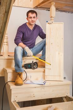 a young worker sitting on ladder and holding one step