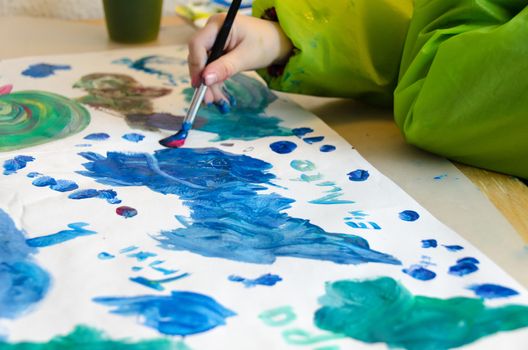 Child painting with an paint brush and water colors on paper