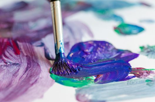 Child painting with an paint brush and water colors on paper